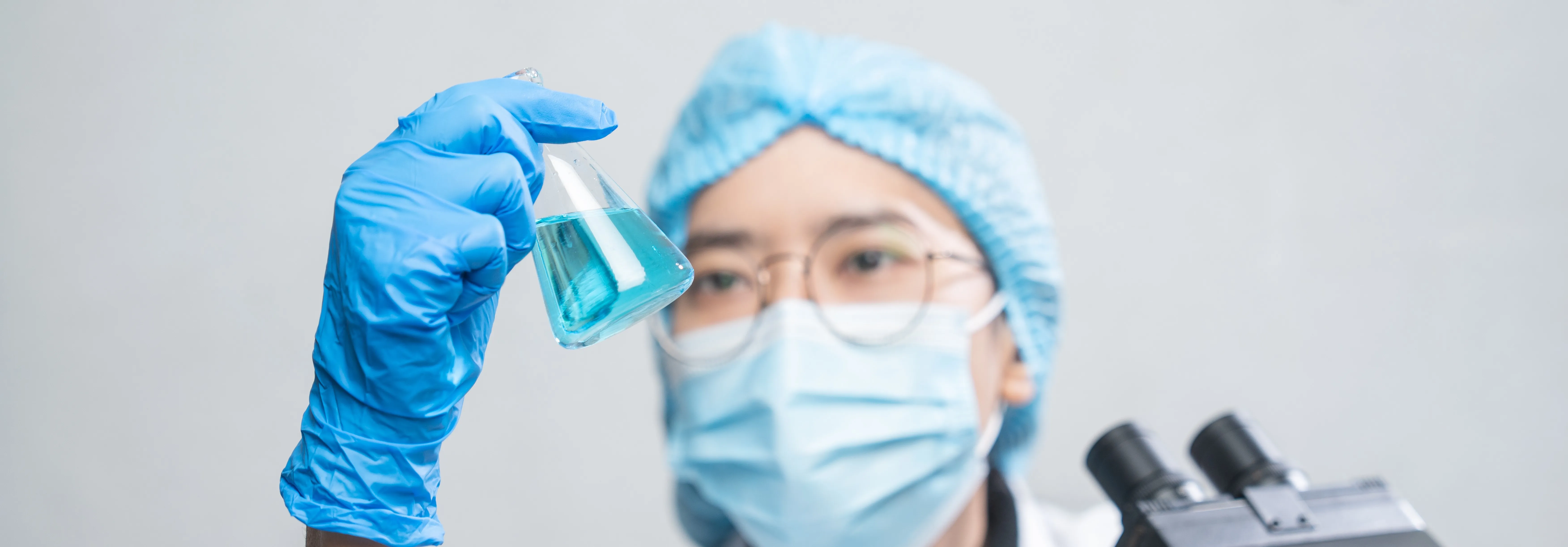 scientist analysing blue liquid in beaker